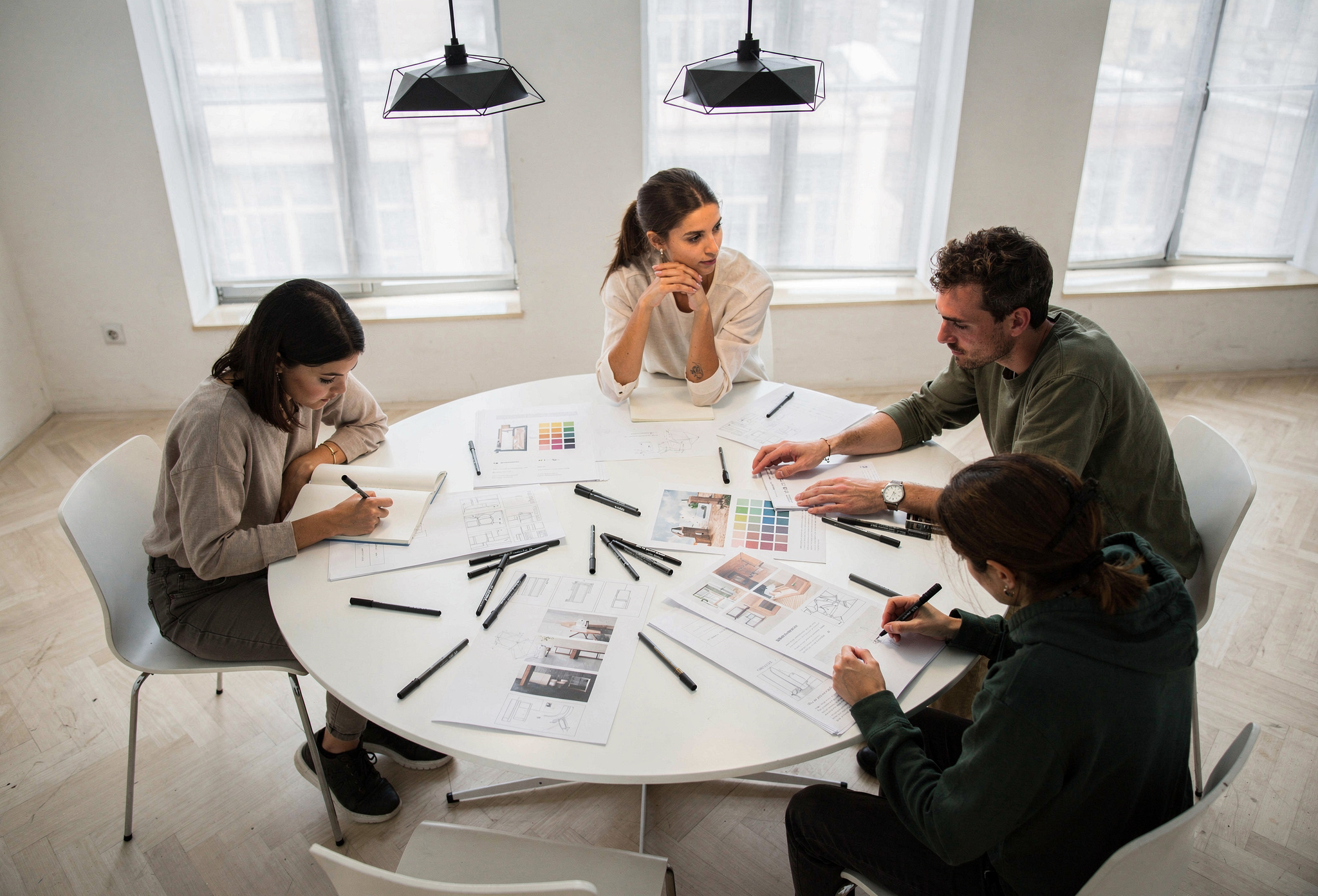 Yuvarlak masa etrafında çalışan dört yaratıcı öğrenci